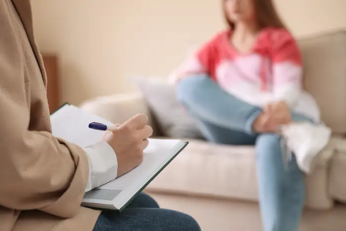 Stock image of young woman sitting on a couch meeting a therapist